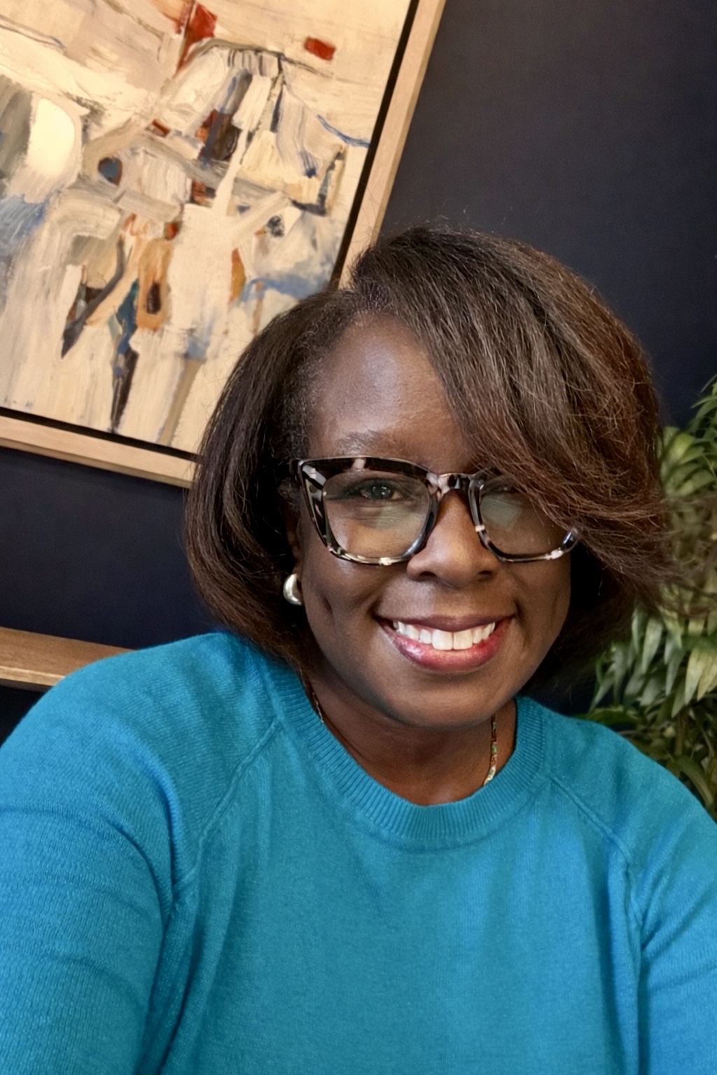 Catherine Clay, smiling, wearing glasses and a teal sweater
